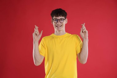 İyi bir sınav için şans dileyen mutlu öğrenci kırmızı arka planda sonuç aldı