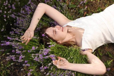 Dışarıda lavanta çiçeklerinin arasında uzanan genç ve güzel bir kadın.