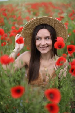 Gülen kadın şapkalı kırmızı gelincik çiçekleri arasında kır çiçeklerinde