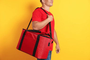 Turuncu arka planda termo çantalı kurye, yakın plan. Yemek dağıtım servisi.