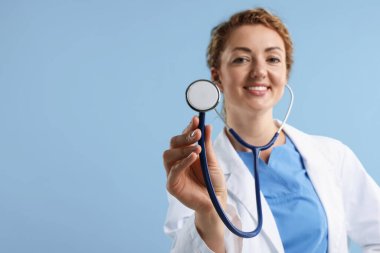 Açık mavi arka planda steteskobu olan profesyonel bir çocuk doktoru, seçici bir odak noktası. Metin için boşluk