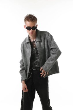 Beyaz arka planda şık ceket ve güneş gözlüğü takan yakışıklı bir genç.