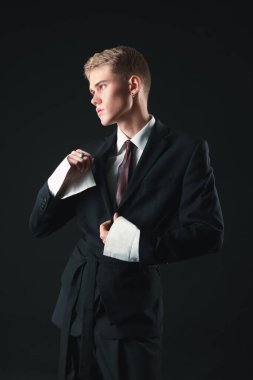 Siyah arka planda şık giyinen yakışıklı genç adam.