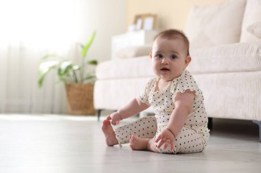 Sevimli küçük bebek evde yerde oturuyor, mesaj için yer var.