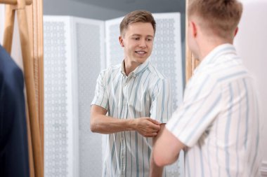 Hazırlanıyor. Genç adam aynanın yanında kıyafet deniyor.