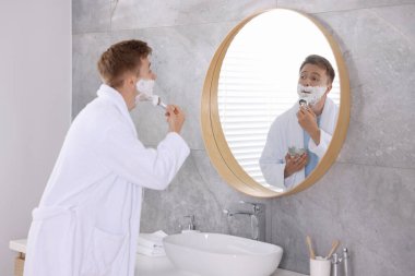 Hazırlanıyor. Genç adam evde aynanın yanında kremayla tıraş oluyor.