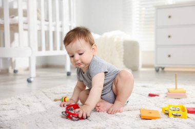 Odada oyuncaklarla oynayan şirin bir bebek.