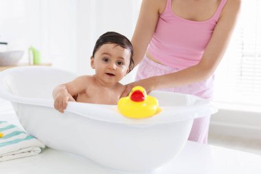 Anne küçük bebeğini evde yıkıyor, yakın plan.