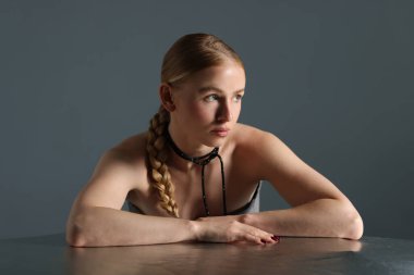 Gri arka planda at kuyruklu güzel bir kadın poz veriyor.