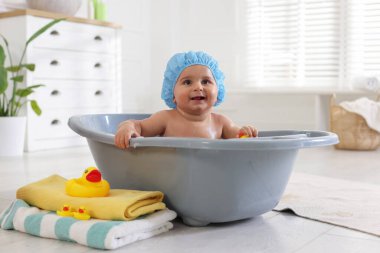 Evde şapkalı şirin bir bebek banyo yapıyor.