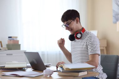 İyi bir sınav sonucunu kutlayan mutlu öğrenci içeride masada.