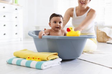 Anne küçük bebeğini evde yıkıyor, yakın plan.