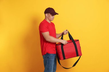 Turuncu arka planda termo çantalı bir kurye. Yemek dağıtım servisi.