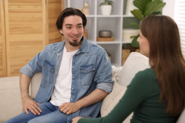 Kadın ve erkek evdeki kanepede konuşuyor.