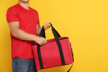 Yemek dağıtım servisi. Turuncu arka planda termo çantalı kurye, yakın plan. Metin için boşluk