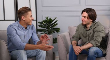 Ofisteki koltuklarda sohbet eden meslektaşlar.