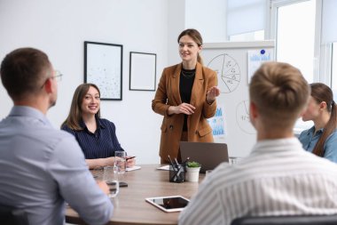 İş koçu ofisteki bir grup insana sunum yapıyor.