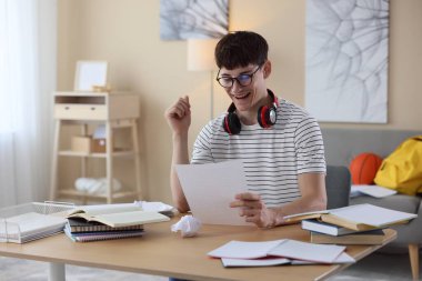 İyi bir sınav sonucunu kutlayan mutlu öğrenci içeride masada.