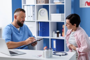 Gastroenterolog klinikte mide ağrısı olan bir hastaya danışmanlık yapıyor.