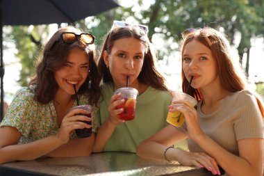 Arkadaşlar açık kafede içeceklerin tadını çıkarıyorlar.