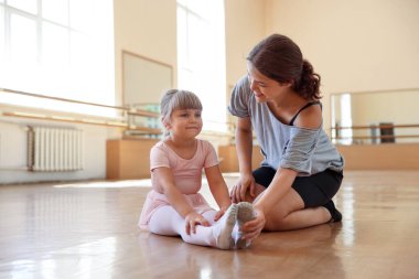 Dans sınıfında küçük bir kızla çalışırken mutlu bir bale öğretmeni.