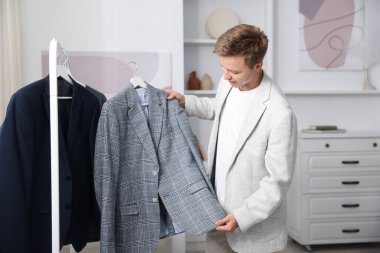 Hazırlanıyor. Genç adam evde kıyafet seçiyor.