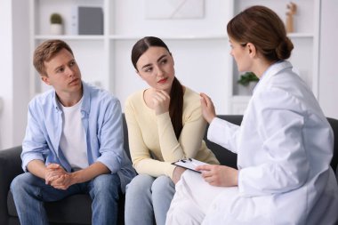 Tüp bebek (tüp bebek). Üreme kliniğine yaptığı ziyarette üzgün çifti destekleyen doktor