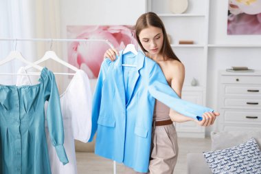 Hazırlanıyor. Evde kıyafet seçen genç bir kadın.