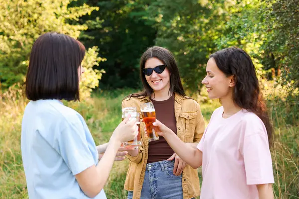 Bir grup mutlu arkadaş dışarıda bira bardaklarını tokuşturuyor.
