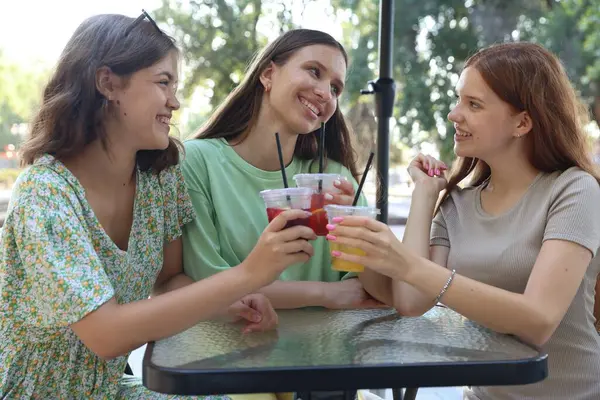 Arkadaşlar açık kafede içeceklerin tadını çıkarıyorlar.