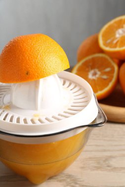 Meyve suyu. Meyve sıkacağı ve taze portakallar ahşap masada, yakın plan.