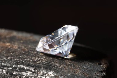 Siyah arkaplana karşı yanmış bir tahta parçasında parlak bir elmas, makro görünüm