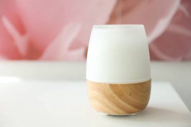 Beyaz ahşap masada modern aroma lambası, yakın plan. Metin için boşluk