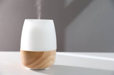 Beyaz ahşap masada gri arka planda modern aroma lambası. Metin için boşluk