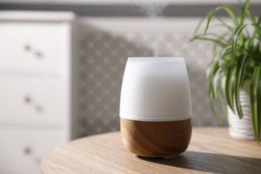 Ahşap masa üzerinde şık bir aroma lambası, yakın plan.