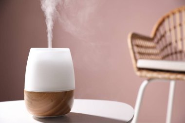 Pembe duvara karşı beyaz masada şık bir aroma lambası, yakın plan. Metin için boşluk