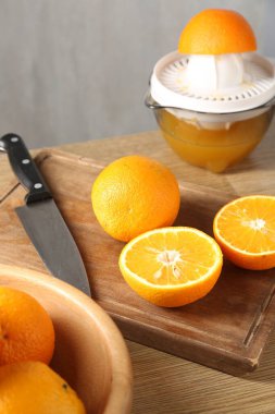 Meyve suyu. Taze portakallar, meyve sıkacağı ve bıçak ahşap masada, yakın plan.