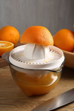 Meyve suyu. Meyve sıkacağı, taze portakal ve bıçak ahşap masada, yakın plan.