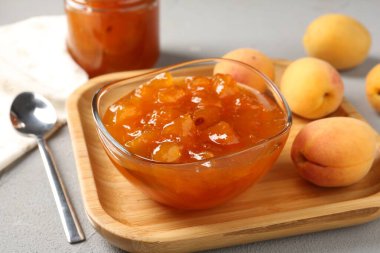 Lezzetli kayısı reçeli ve açık gri masada taze meyveler. Yakın plan.