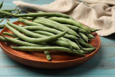 Mavi ahşap masada bir sürü çiğ yeşil fasulye, yakın plan.