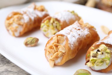 Ricotta peynirli, fıstıklı, şam fıstıklı ve pudra şekerli nefis cannoli. Gri desenli masa, yakın plan.