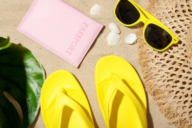 Yaz tatili zamanı. Pasaport, yeşil yaprak ve kumsaldaki aksesuarlar.