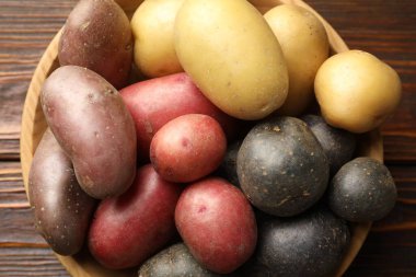 Tahta masadaki kasede farklı patates türleri, üst manzara.