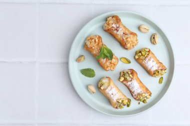Peynirli, fındıklı ve naneli nefis cannoli, beyaz fayanslı masa, üst manzara. Metin için boşluk