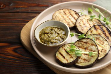 Ahşap masada soslu ızgara patlıcan dilimleri ve mikroyeşiller, yakın plan.