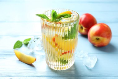 Şeftalili buzlu çay ve açık mavi ahşap masada nane, yakın plan.