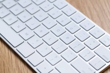 Modern beyaz kablosuz klavye ahşap masada, yakın plan