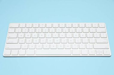 Açık mavi arkaplanda modern beyaz kablosuz klavye