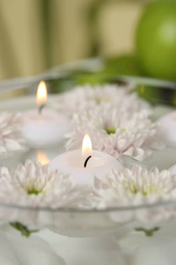 Bulanık arka planda yanan mumlar ve çiçekler, yakın plan.