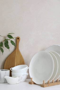 Farklı beyaz bulaşık takımları, ahşap kesim tahtaları ve mutfak tezgahında bitki örtüsü, mesaj için yer.